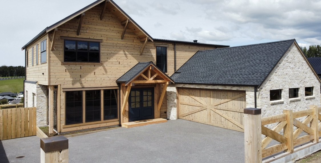 Front elevation in daylight, timber cladding, stone base and garaging