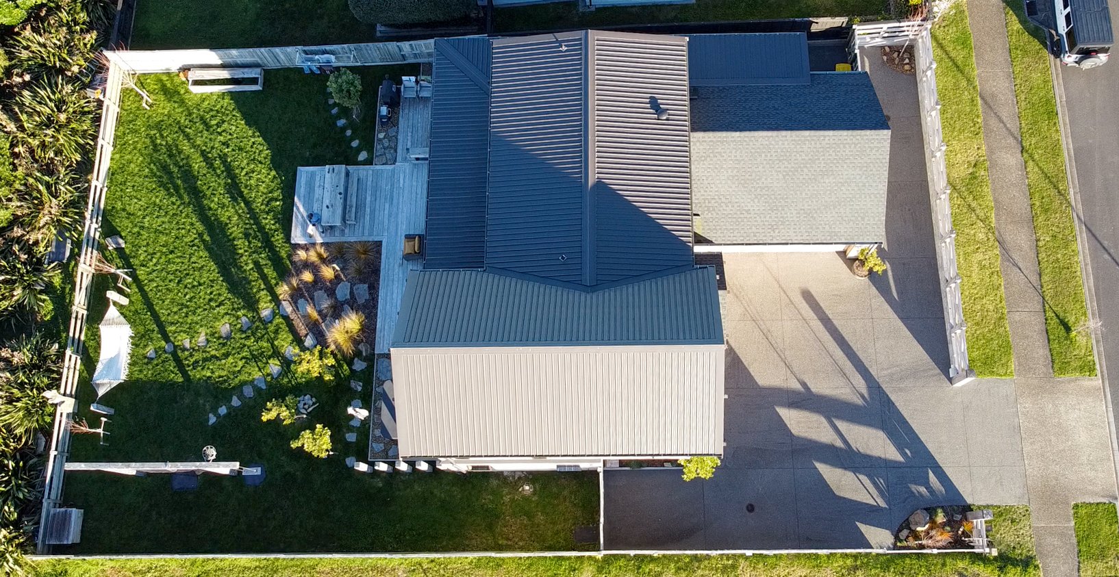 Top down aerial of the site showing the fully fenced backyard, decks, covered alfresco and driveway parking