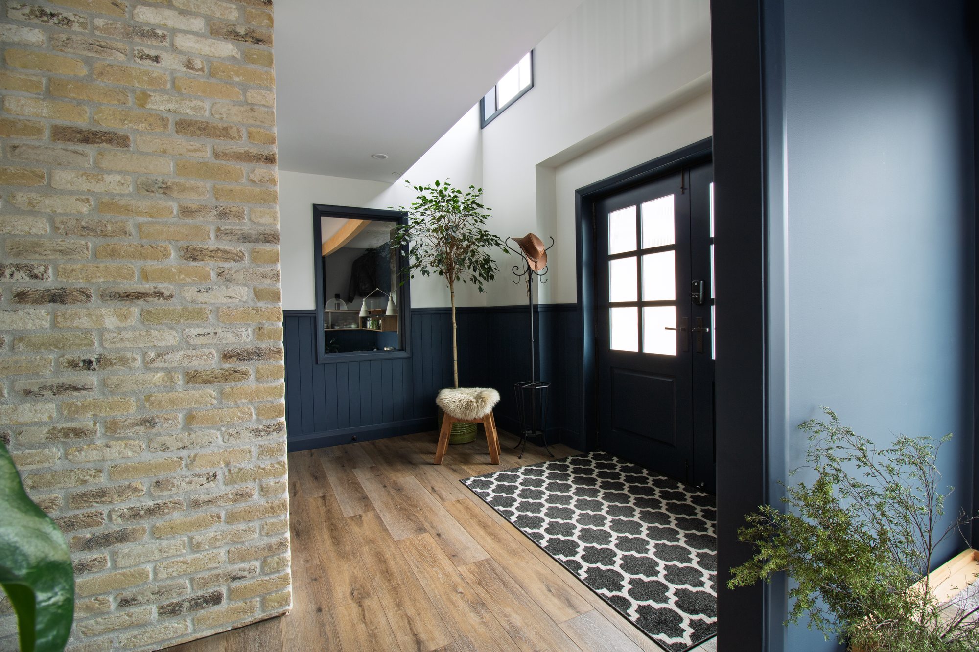 Entry hall with Belgian brick wall, custom cedar front door and fluted glass